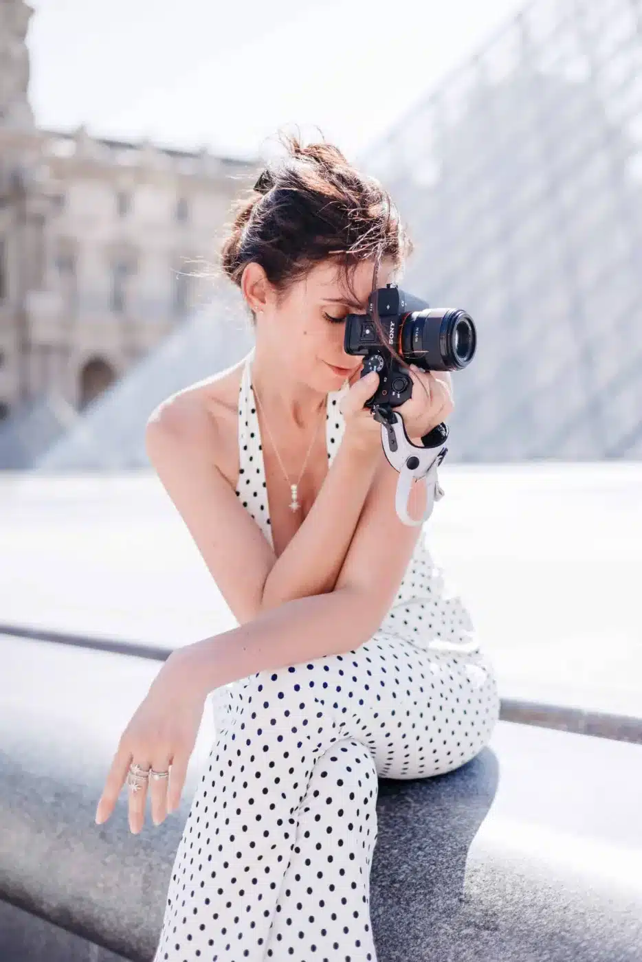 Sandra Da Silva, photographe portraitiste à Paris 16, son appareil photo Sony à la main devant le Louvre
